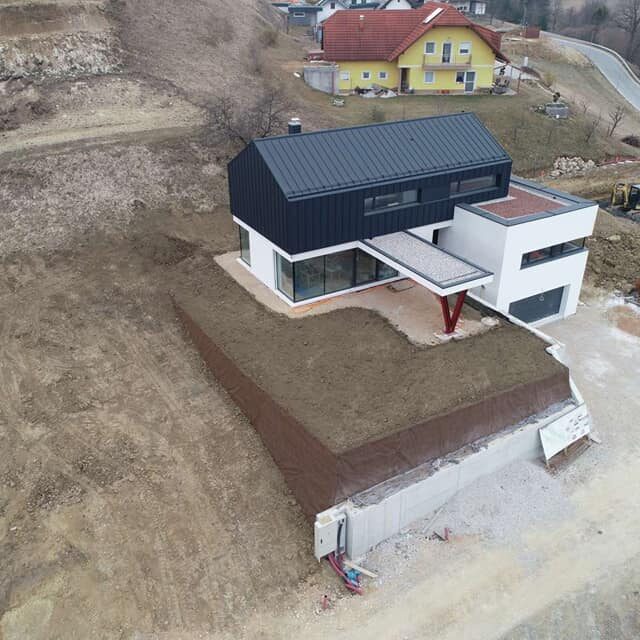 Zgrajena zemljena škarpa ob sodobni enodružinski hiši, posnetek iz zraka.